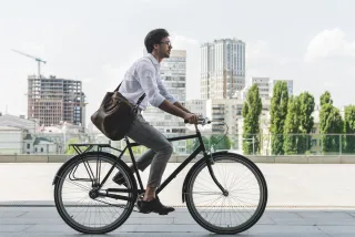 A man in a suit riding a bike on a city street.