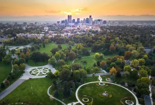 Aerial view of Denver skyline with skyscrapers and mountains in the background.