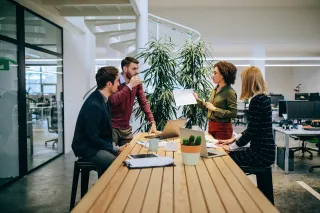 Three professionals having a meeting at a conference table in an office setting.