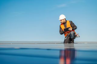 A worker using tablet to test solar panels