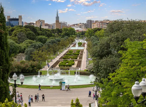 A serene park with a beautiful fountain surrounded by lush trees, offering a peaceful and refreshing ambiance.