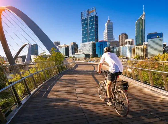 A man cycling on a bridge over a city.