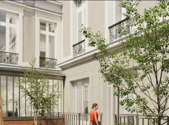 A courtyard with a tree in the middle and a building in the background.